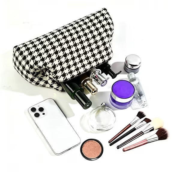 Makeup bag with makeup items including brushes, bottles, and a phone on a white background